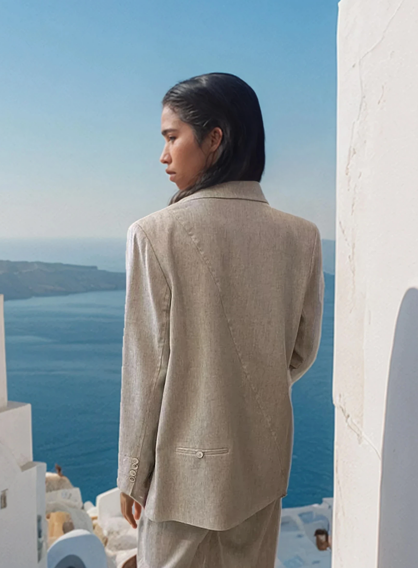 Woman wearing a natural-tone cotton-linen blazer with a tailored fit, photographed on a Santorini street.