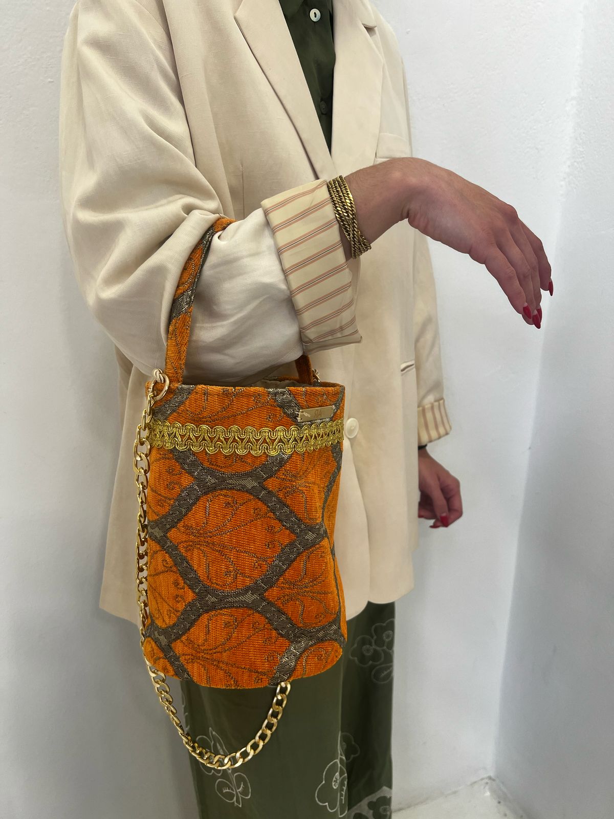 Structured jacquard fabric bucket bag with a gold-tone chain strap and top handle, displayed against a plain white background.