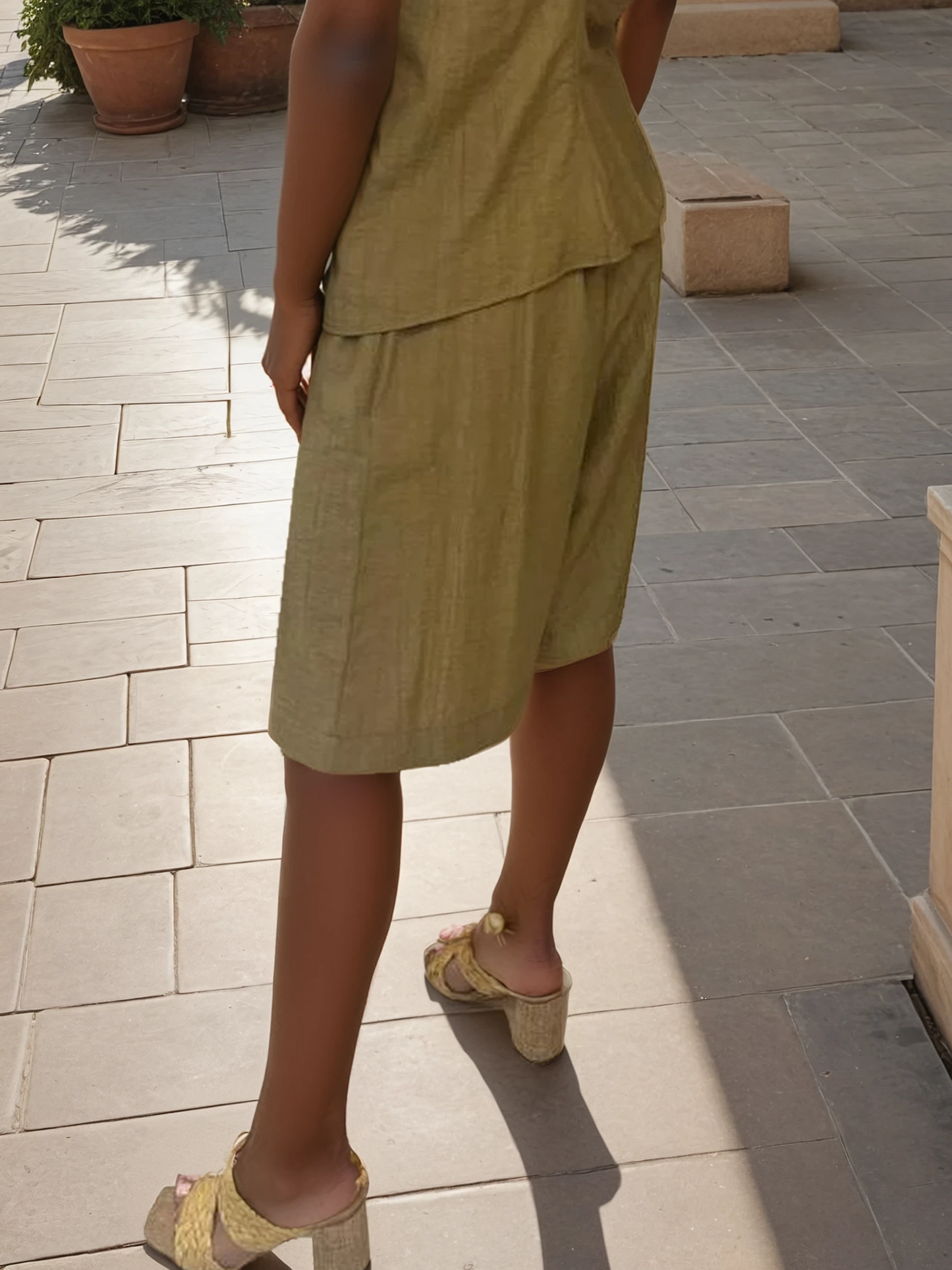 Tailored bermuda shorts in natural fabric styled with a draped strapless top and block-heel sandals.